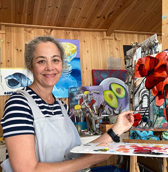 Portrait of Farida Khan-Evans in her studio surrounded by her paintings